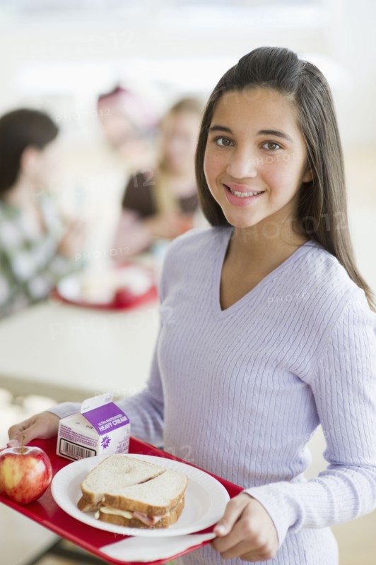 Girl holding tray of cafeteria food.
