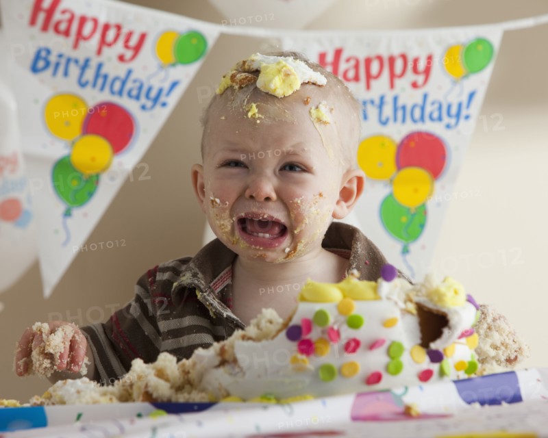 Baby covered in birthday cake. Photographer: Mike Kemp