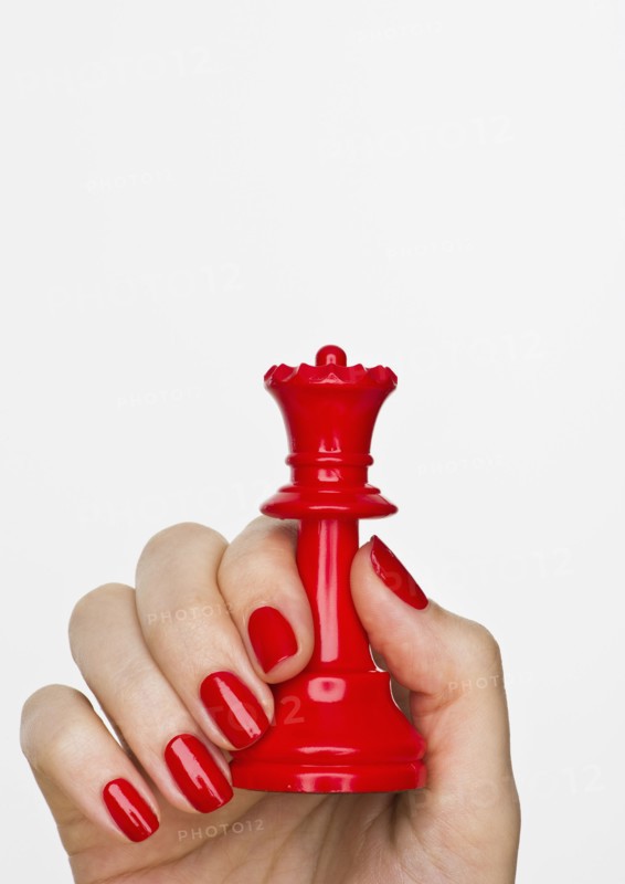 Hand holding red queen chess piece.
