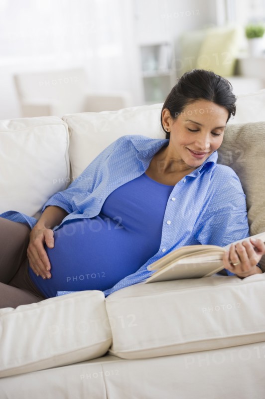 Pregnant woman reading on couch.