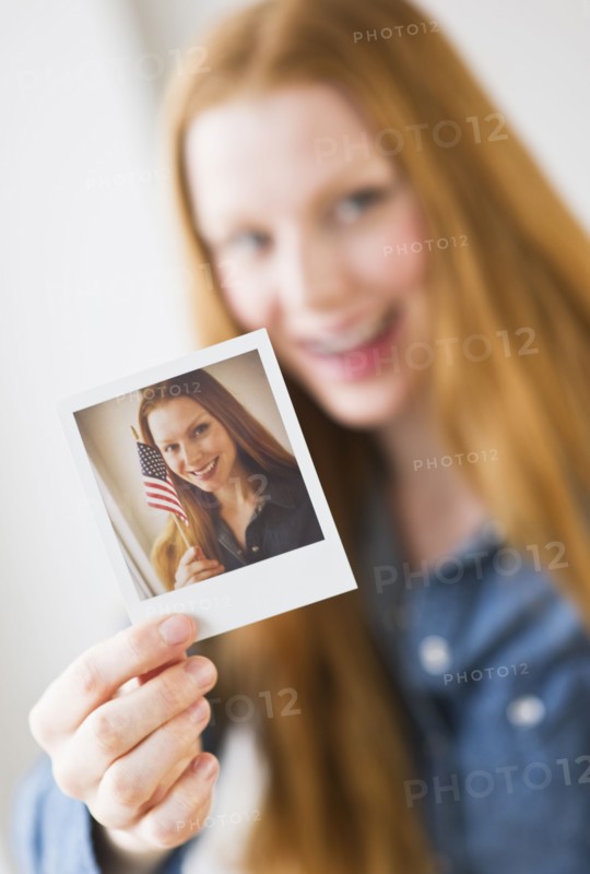 Woman holding photograph of herself.