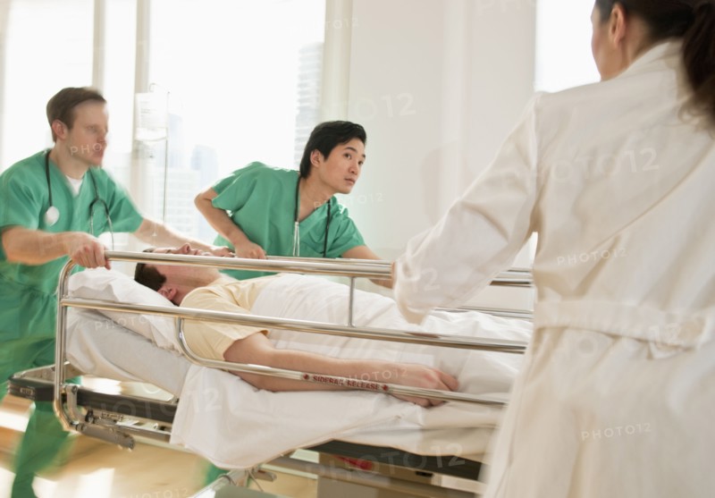Healthcare workers pushing gurney in emergency room.