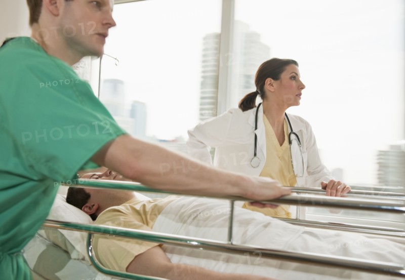 Healthcare workers pushing gurney in emergency room.