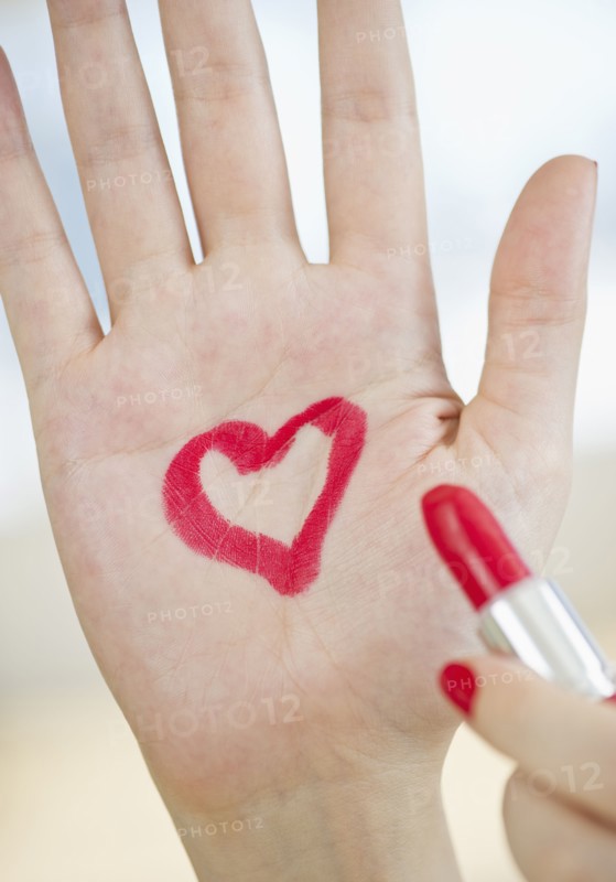 Red heart drawn on hand with lipstick.