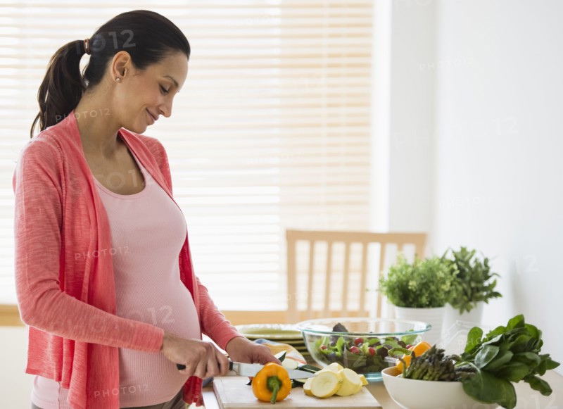 Pregnant woman making salad.