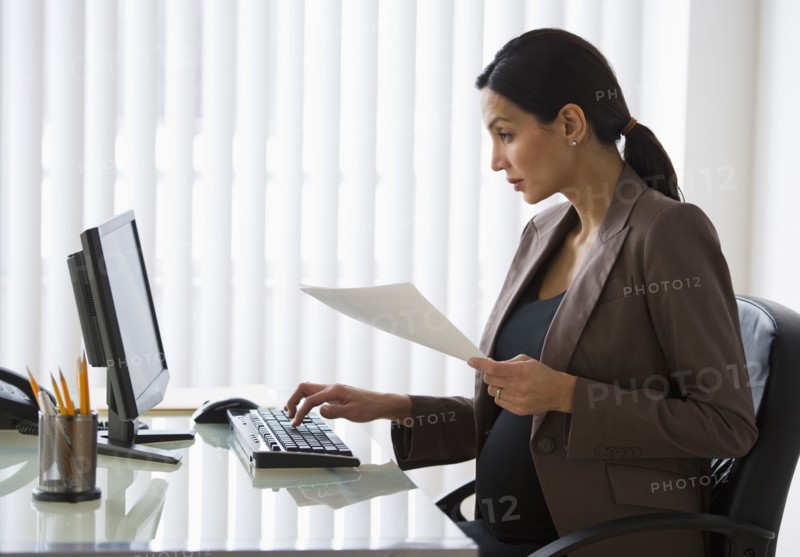 Pregnant businesswoman working on computer.