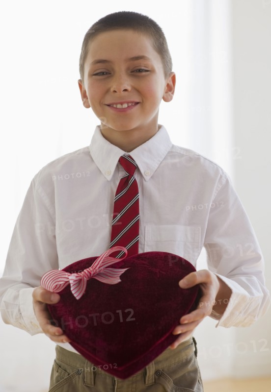 Young boy holding a box of chocolates.