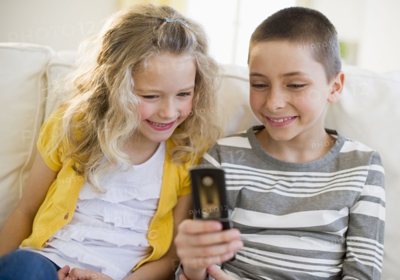 Siblings looking at cellular phone.
