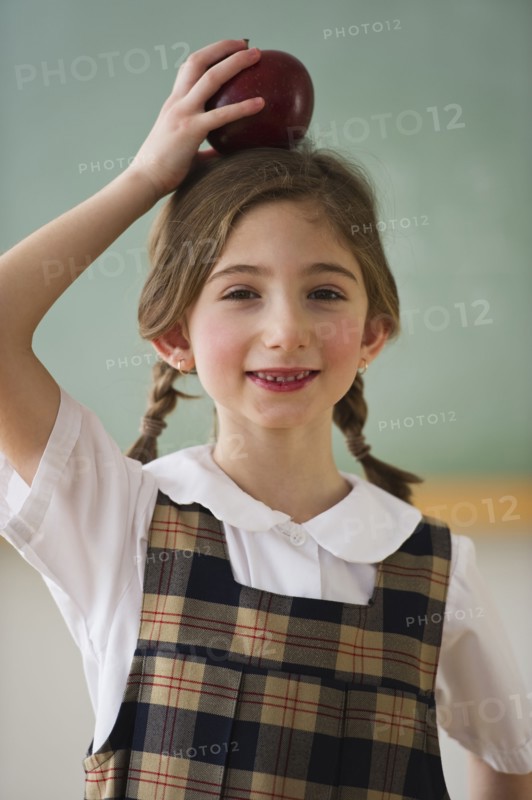 Child holding an apple on her head. Photographe : Daniel Grill