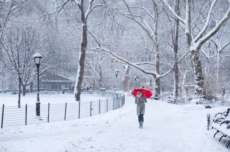 Woman walking with red umbrella on a snowy day. Photographe : Daniel Grill