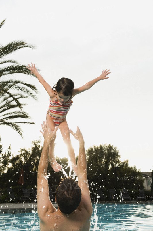 Father and daughter playing in pool.