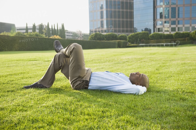 Businessman relaxing on lawn.