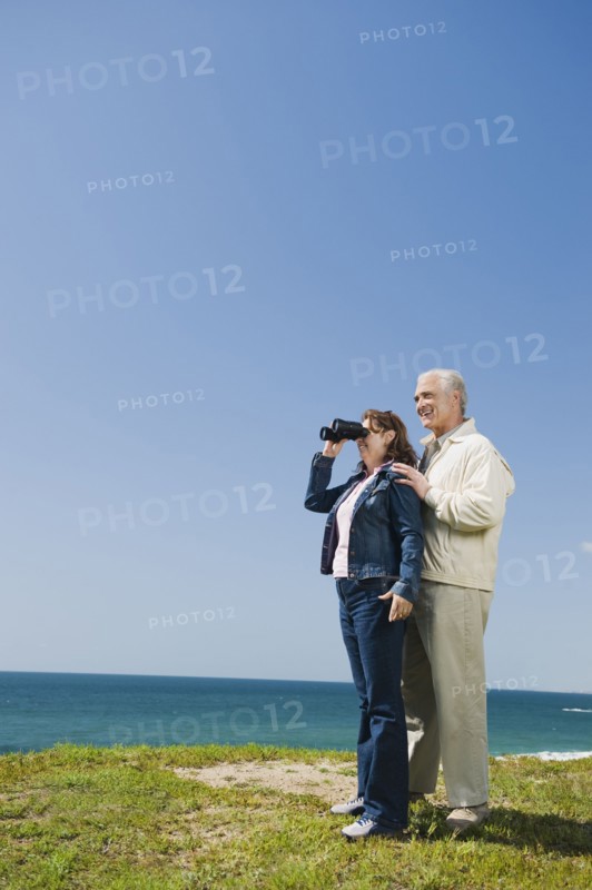 Couple looking at ocean with binoculars.