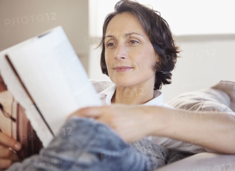 Woman reading on couch. Photographe : momentimages
