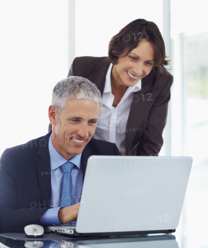 Colleagues looking at laptop. Photographe : momentimages