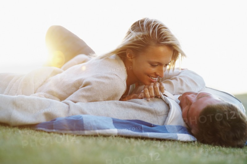 Couple lying down on picnic blanket. Photographe : momentimages