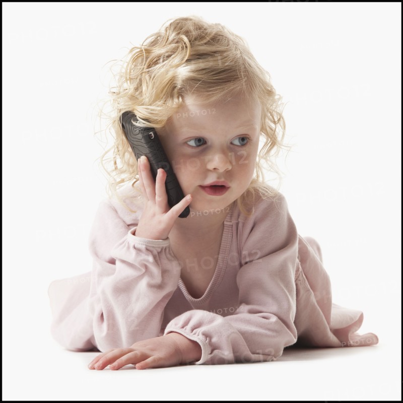 Young girl playing with a cellular phone. Photographe : Mike Kemp