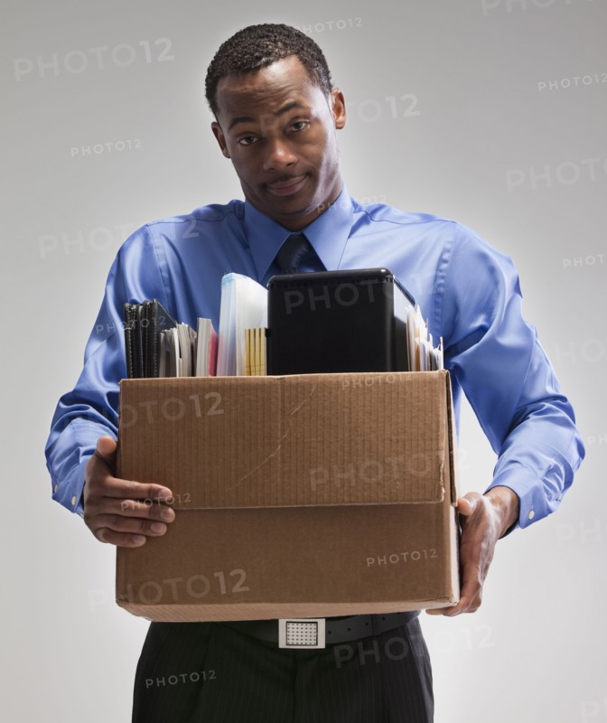 Businessman holding a box of office supplies. Photographe : Mike Kemp