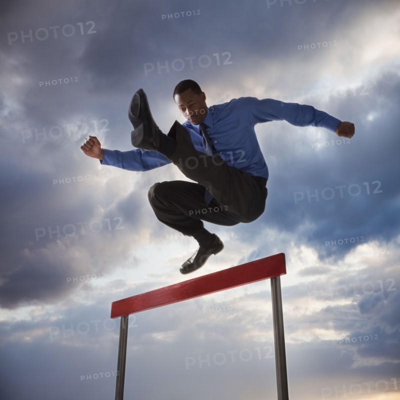 Businessman jumping over a hurdle. Photographe : Mike Kemp