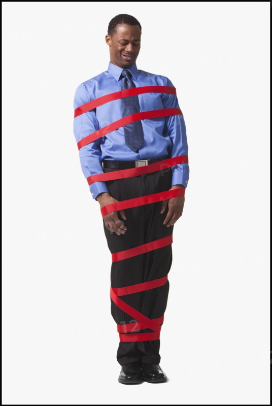 Businessman wrapped in red tape. Photographe : Mike Kemp