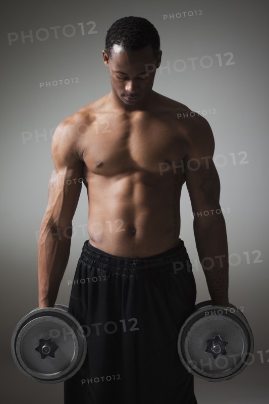 Muscular man lifting dumbbells. Photographe : Mike Kemp