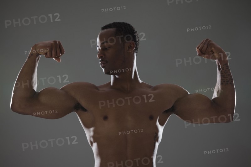Physically fit man flexing his triceps. Photographe : Mike Kemp