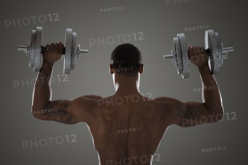 Physically fit man lifting dumbbells. Photographe : Mike Kemp