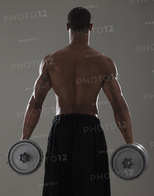 Physically fit man lifting dumbbells. Photographe : Mike Kemp