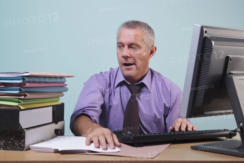 Overworked man sitting at his desk. Photographe : RTimages