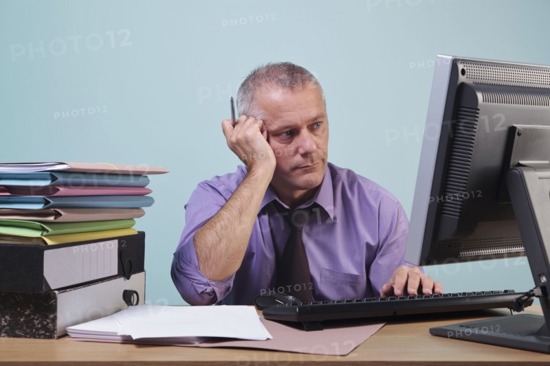 Overworked man sitting at his desk. Photographe : RTimages