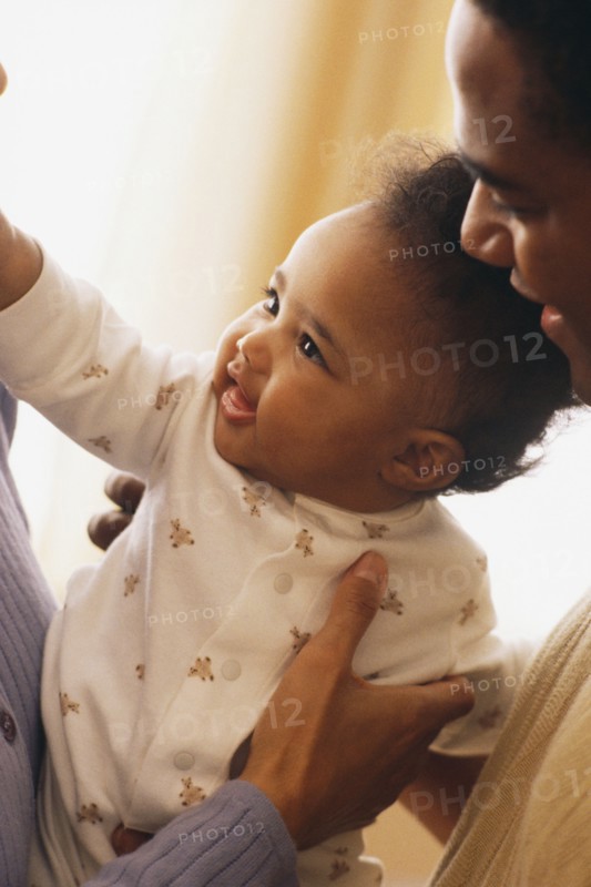 Close-up of mother and father holding their baby. Photographe : Rob Lewine
