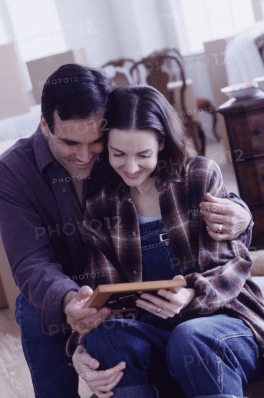 Couple looking at a framed photograph. Photographe : Rob Lewine