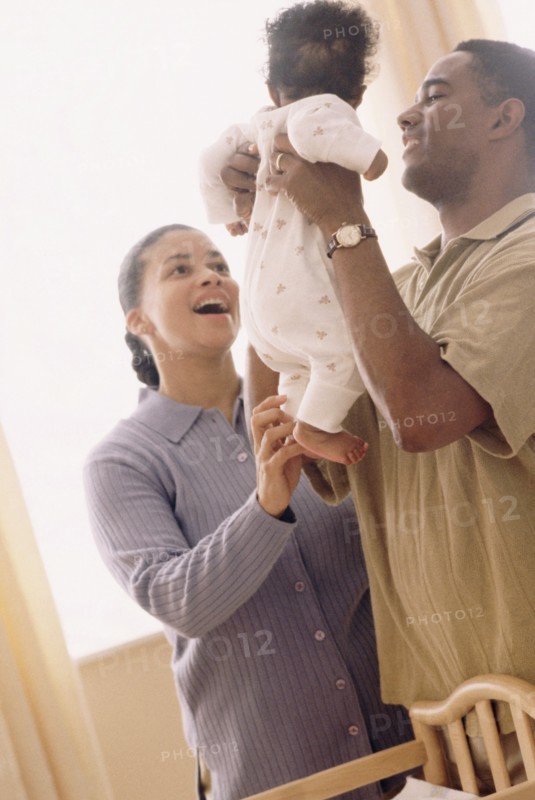 Father picking up his baby. Photographe : Rob Lewine