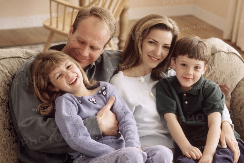 Family sitting together on the couch. Photographe : Rob Lewine