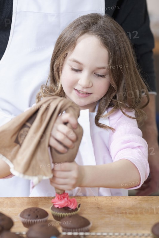 Young girl decorating cupcakes. Photographe : Dan Bannister