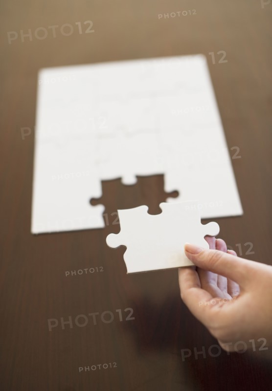 Hand putting last puzzle piece in puzzle.