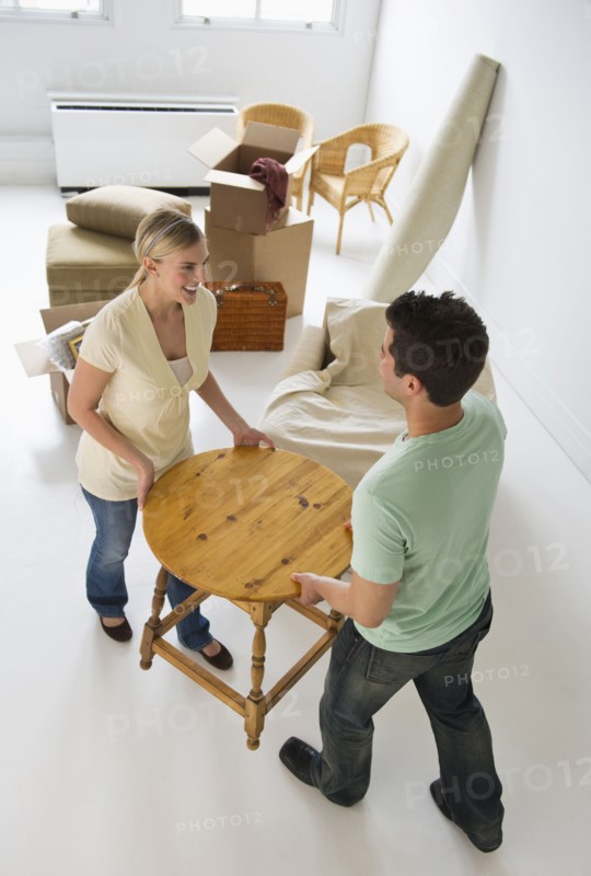 Couple moving furniture in their new home.
