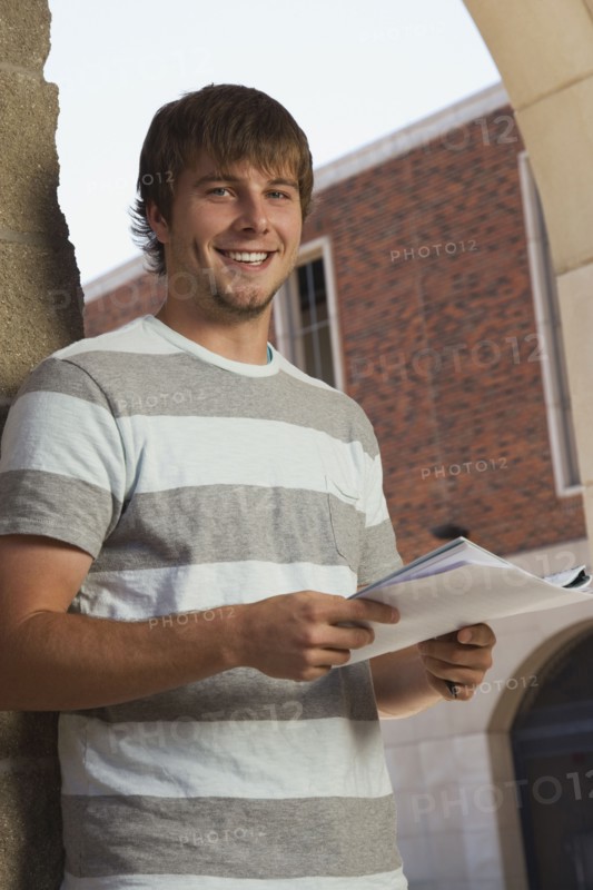 Happy teenage boy holding schoolwork. Photo : Stewart Cohen