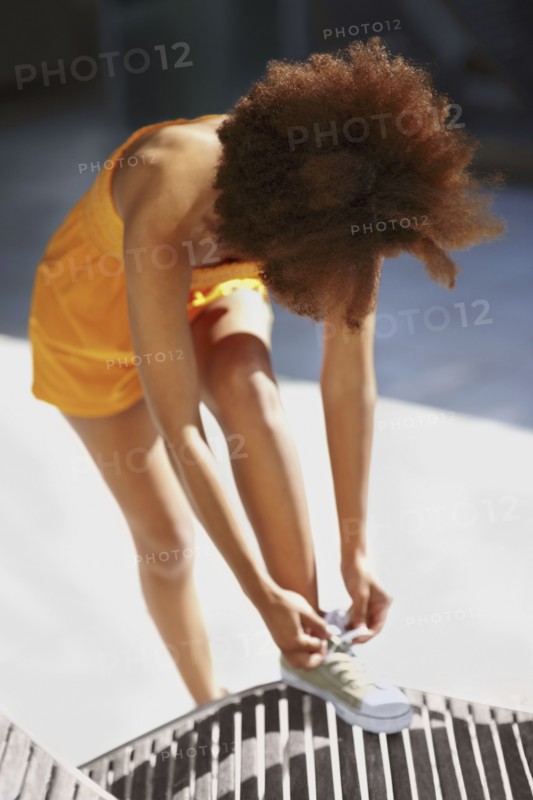 Woman tying her shoelace. Photo : momentimages