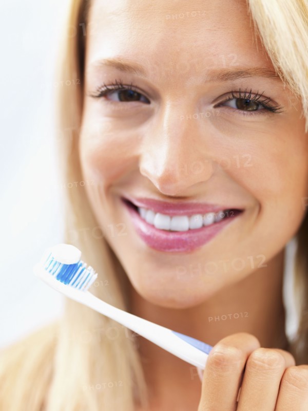 Woman holding a toothbrush. Photo : momentimages