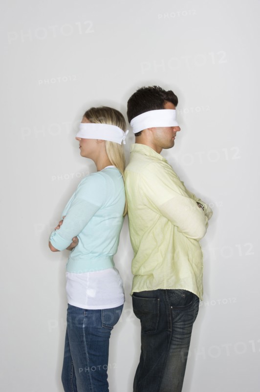 Blindfolded couple standing back to back.