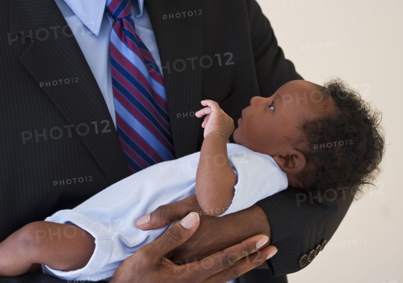 Businessman holding baby. Photo : Daniel Grill