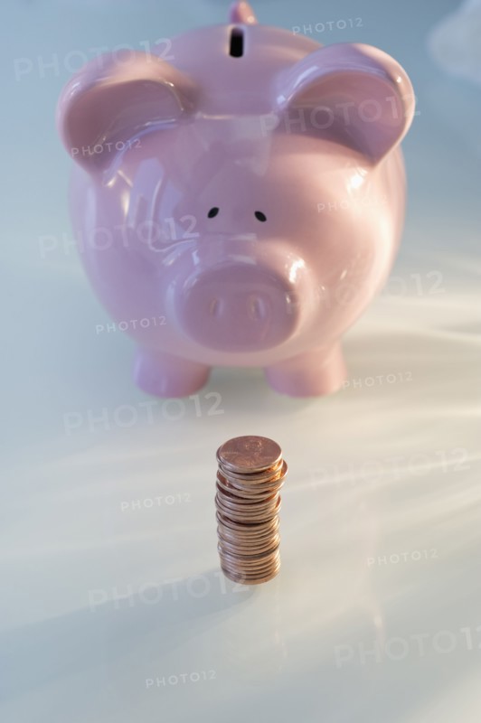 Stack of pennies in front of piggy bank.