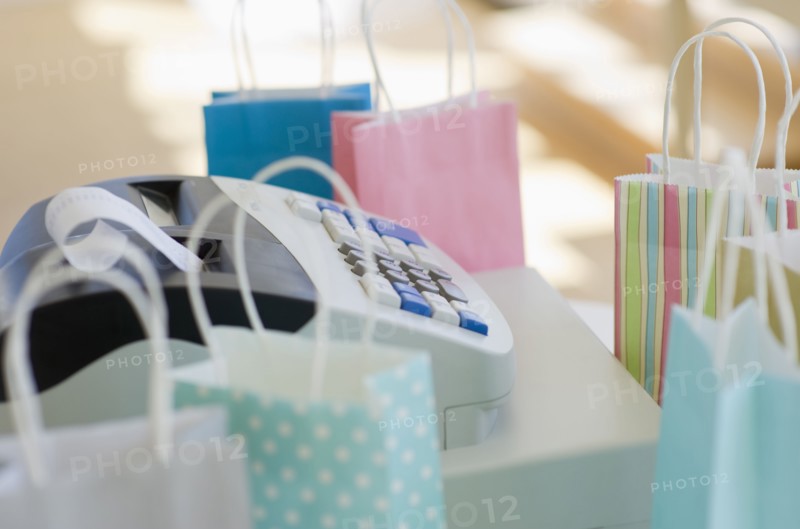 Cash register surrounded by colorful shopping bags.