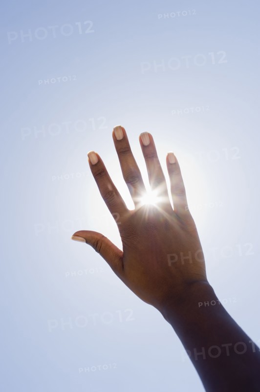 Hand held up in front of sunshine.