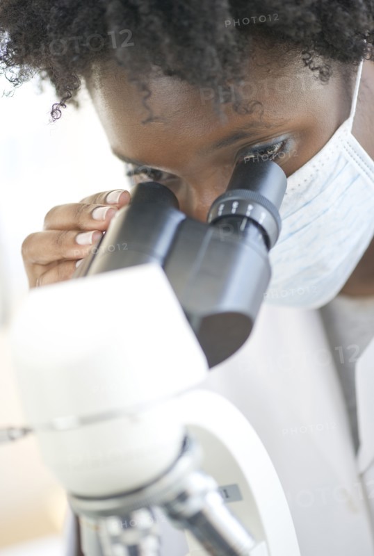 Researcher looking at specimen through microscope.