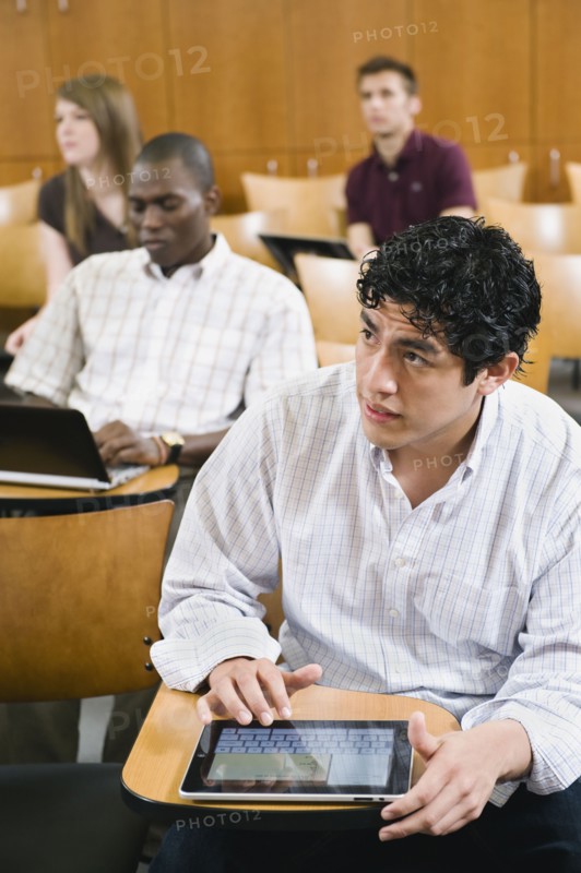College students taking notes in lecture hall.