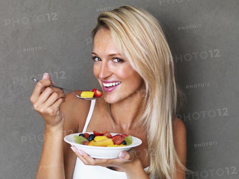 Blond woman eating fresh fruit salad. Photo : momentimages