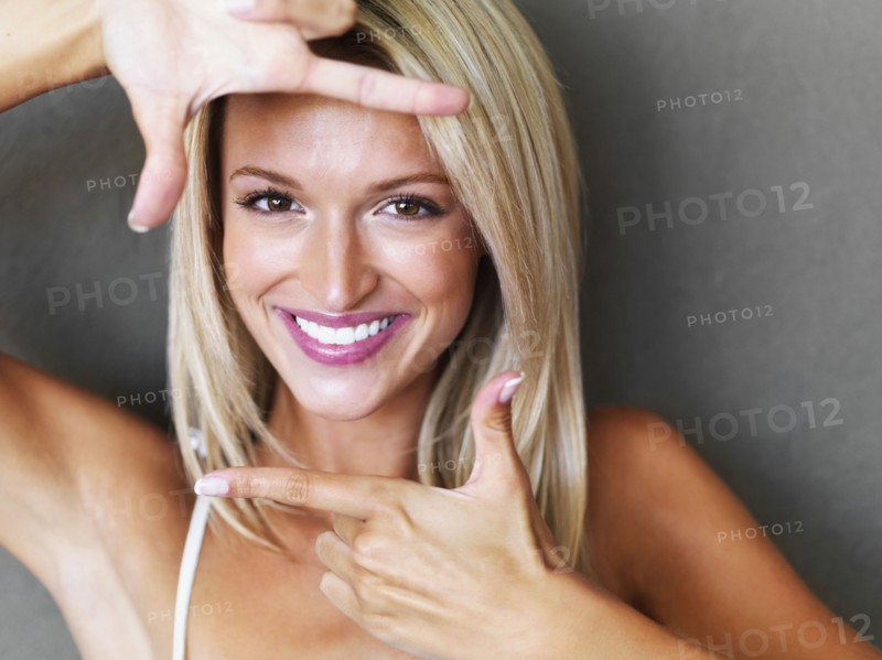 Blond woman making a hand frame around her face. Photo : momentimages