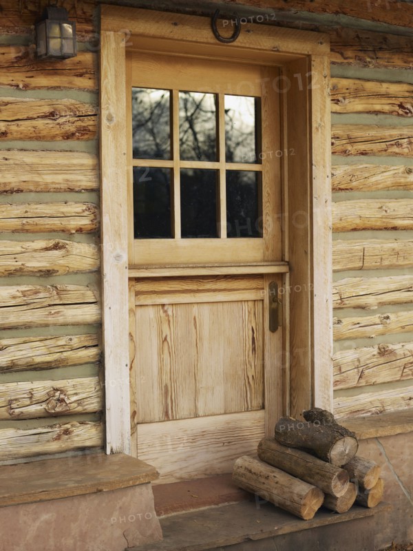 Firewood in front of door of log cabin. Photo : John Kelly